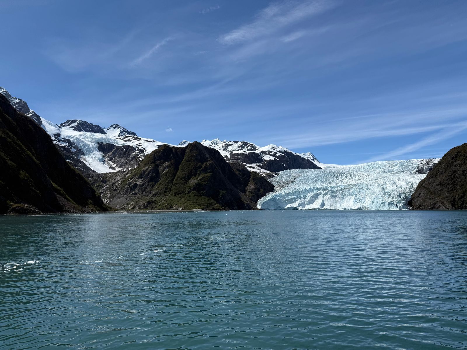 Glacier spilling into a fjord between snowy peaks, the kind of view a solo cruise to Alaska is built around