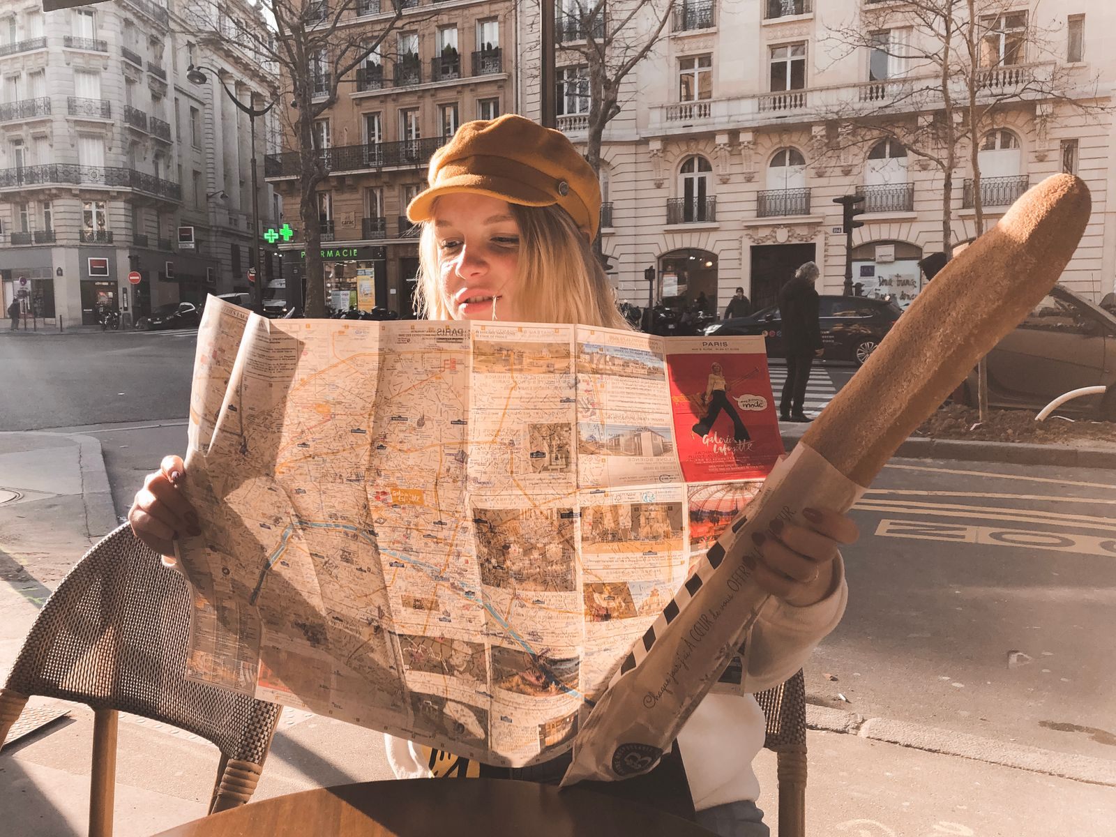 Woman reading a large city map at a street cafe while traveling alone
