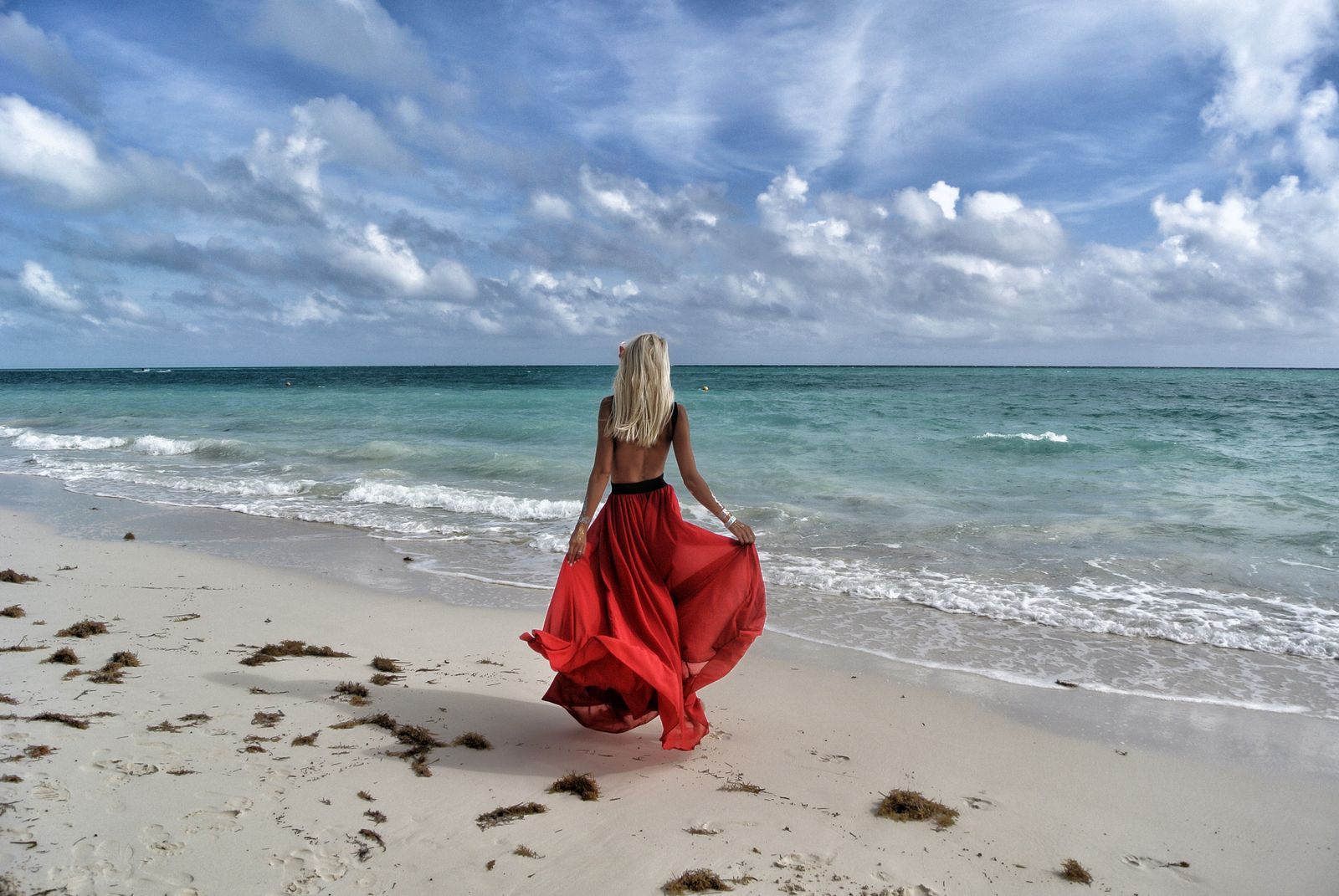Woman in a red dress walking alone along a Bahamas beach, a short hop on solo cruises from Florida