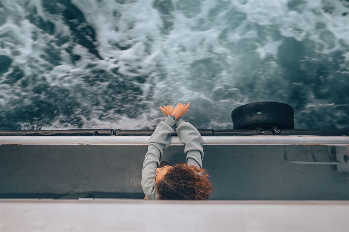 Traveler leaning over a ship rail watching the wake